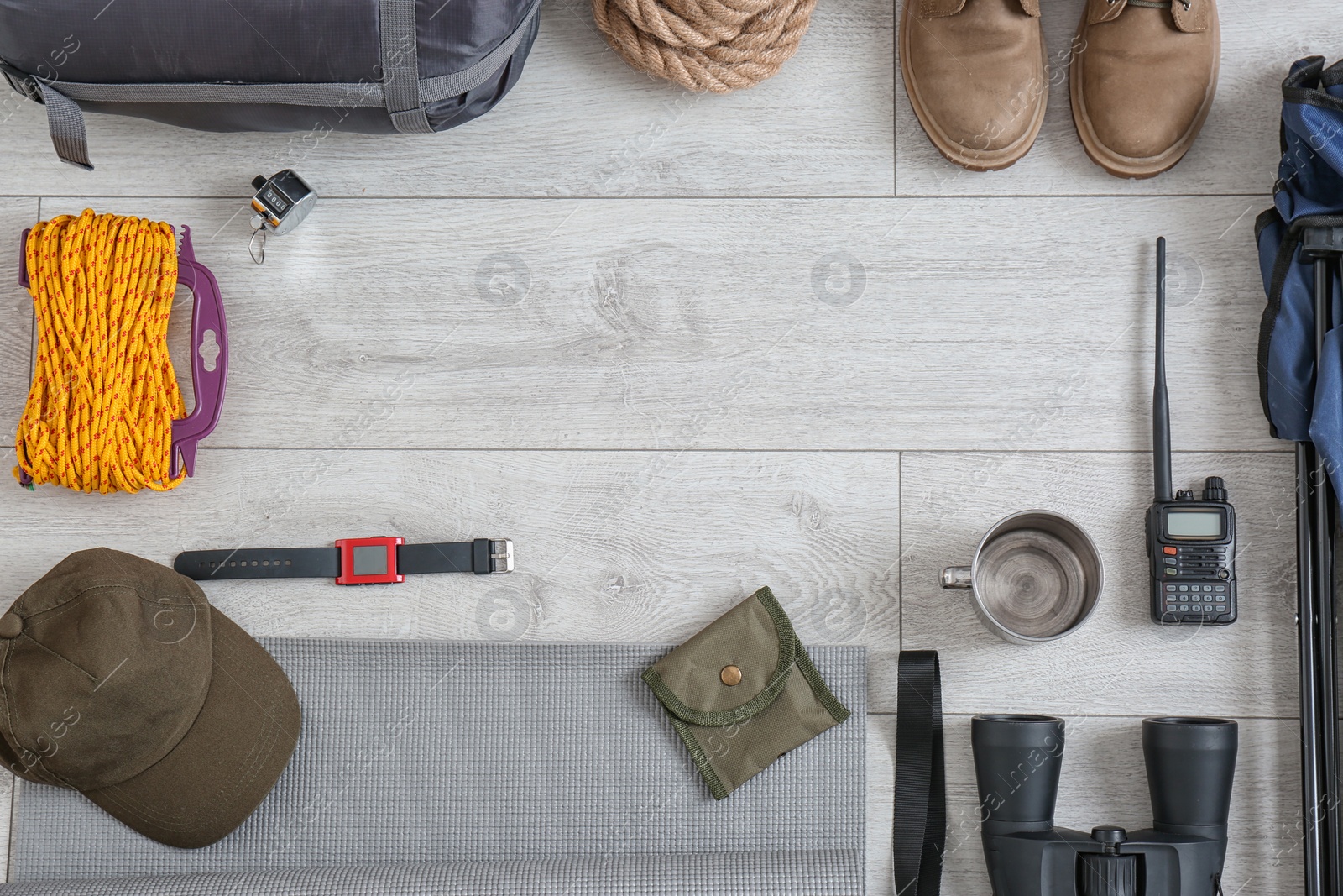 Photo of Flat lay composition with sleeping bag and camping equipment on wooden background. Space for text