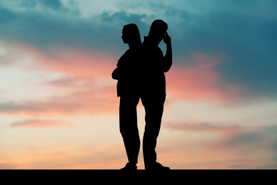 Image of Silhouettes of arguing couple against sunset sky with clouds. Relationship problems