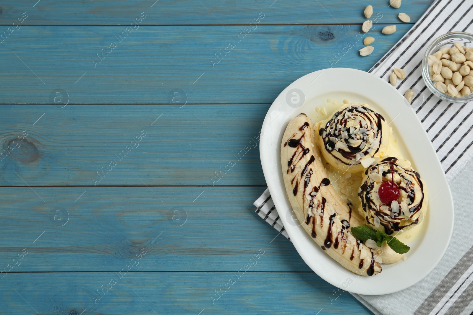 Photo of Delicious dessert with banana ice cream on light blue wooden table, flat lay. Space for text