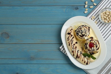 Photo of Delicious dessert with banana ice cream on light blue wooden table, flat lay. Space for text