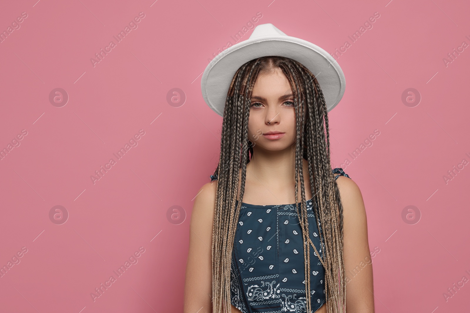 Photo of Beautiful woman with long african braids and hat on pink background, space for text