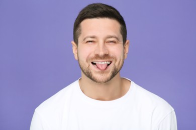 Photo of Happy man showing his tongue on purple background
