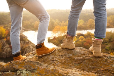 Photo of Couple wearing stylish hiking boots on steep cliff, closeup