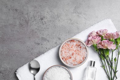 Spa composition with sea salt and beautiful flowers on grey table, flat lay. Space for text