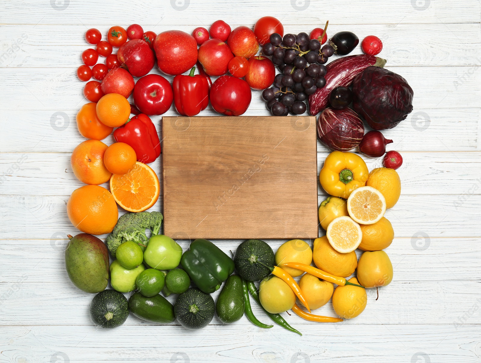 Photo of Board in rainbow frame of fruits and vegetables on wooden background