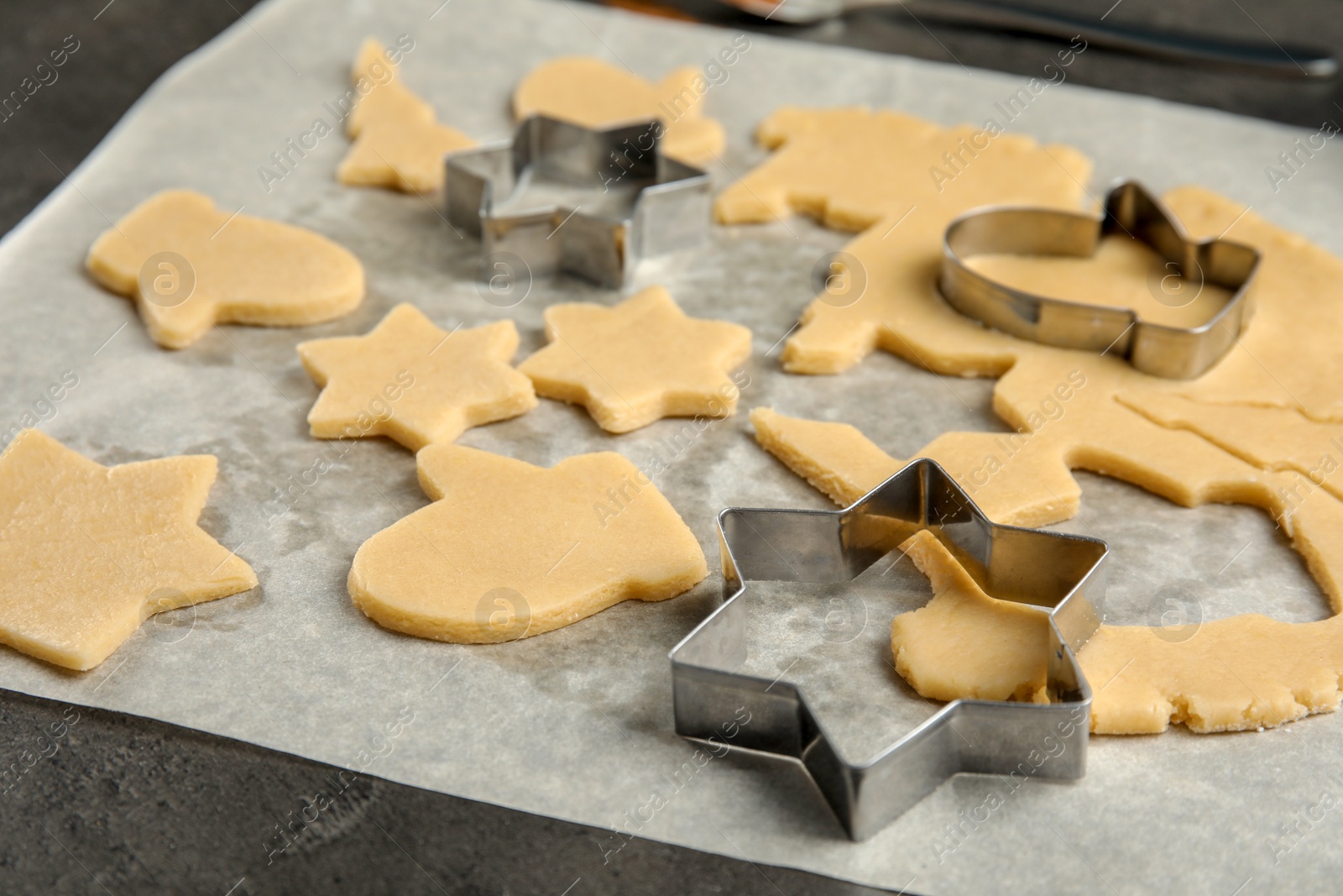 Photo of Cutters and raw Christmas cookies on table. Festive treats