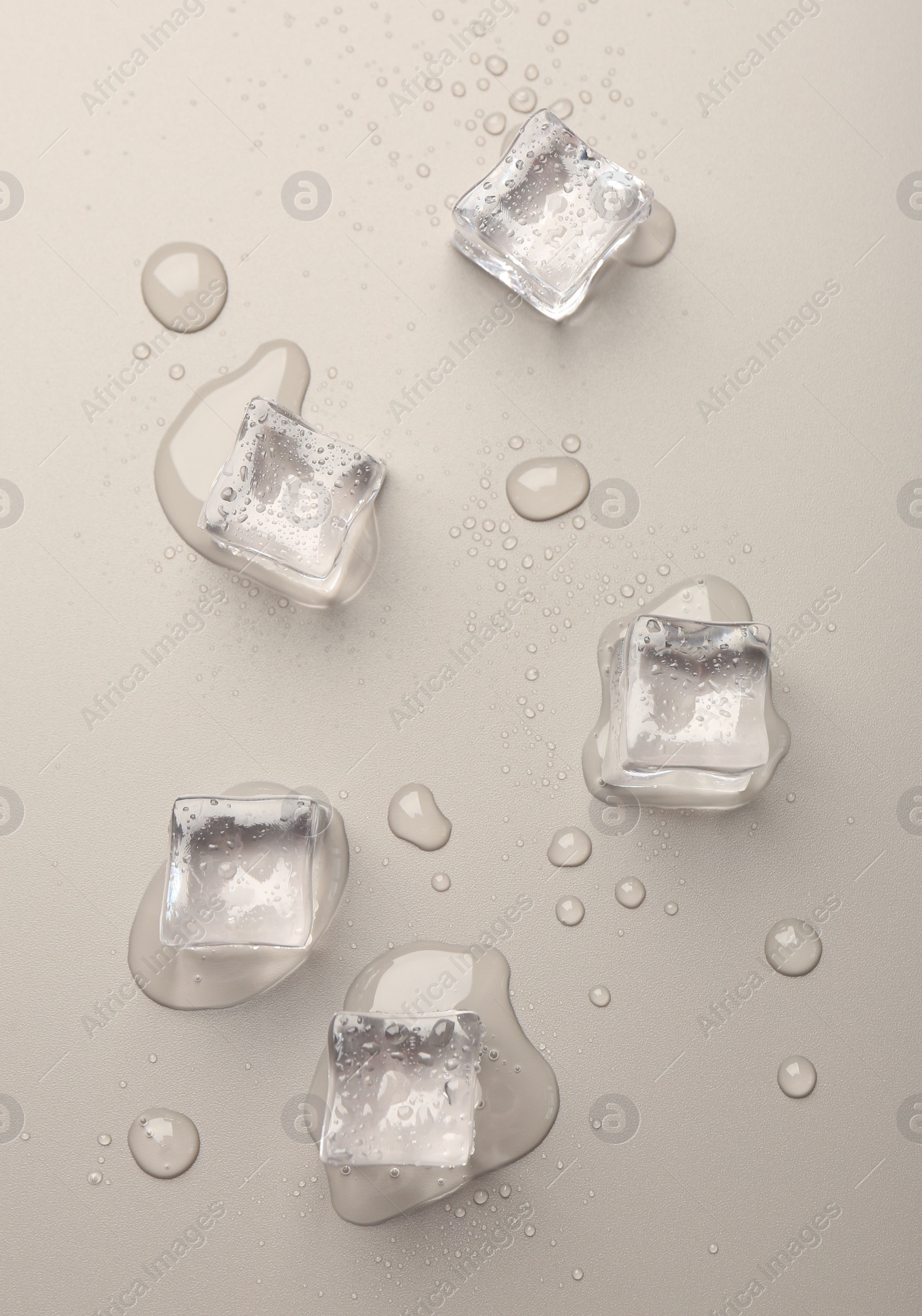 Photo of Melting ice cubes and water drops on light grey background, flat lay