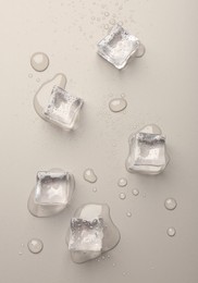 Melting ice cubes and water drops on light grey background, flat lay