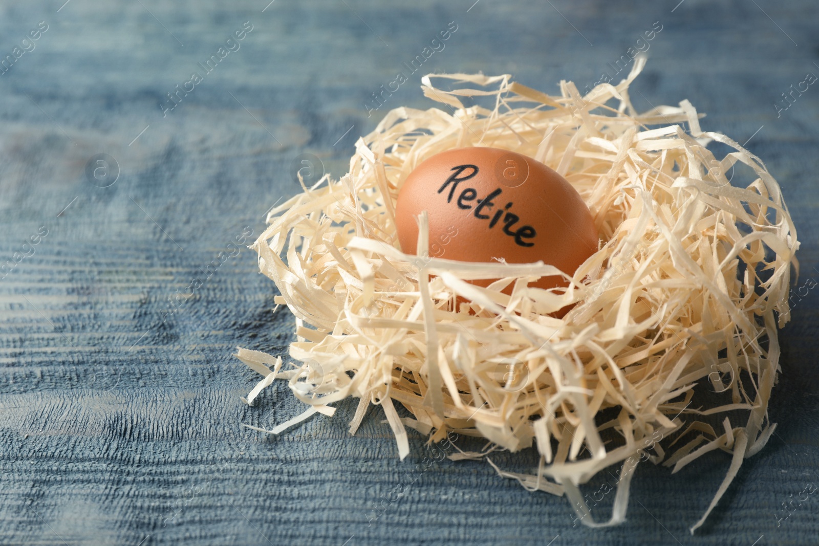 Photo of Egg with word RETIRE in nest on wooden background. Pension concept