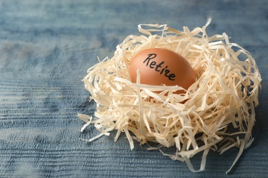 Photo of Egg with word RETIRE in nest on wooden background. Pension concept