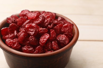 Photo of Tasty dried cranberries in bowl on light wooden table, closeup