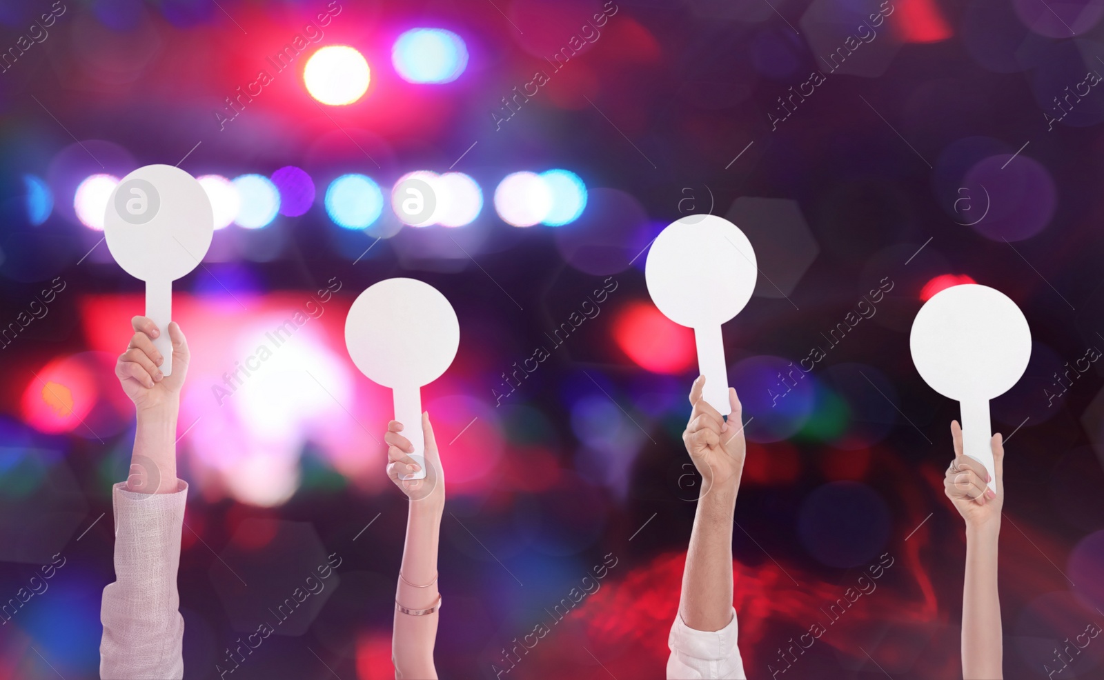 Image of Panel of judges holding blank score signs against blurred background, closeup. Bokeh effect
