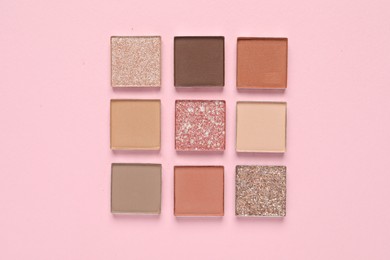 Different beautiful eye shadows on pink background, flat lay