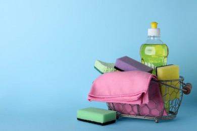 Photo of Sponges and other cleaning products on light blue background. Space for text