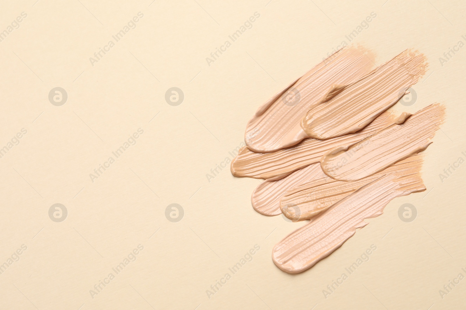 Photo of Samples of skin foundation on beige background, flat lay. Space for text