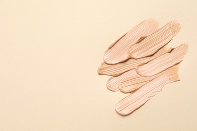 Samples of skin foundation on beige background, flat lay. Space for text