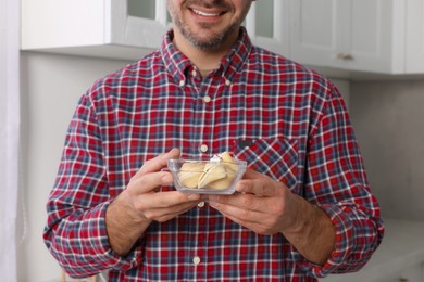 Happy man holding tasty fortune cookies with predictions indoors, closeup