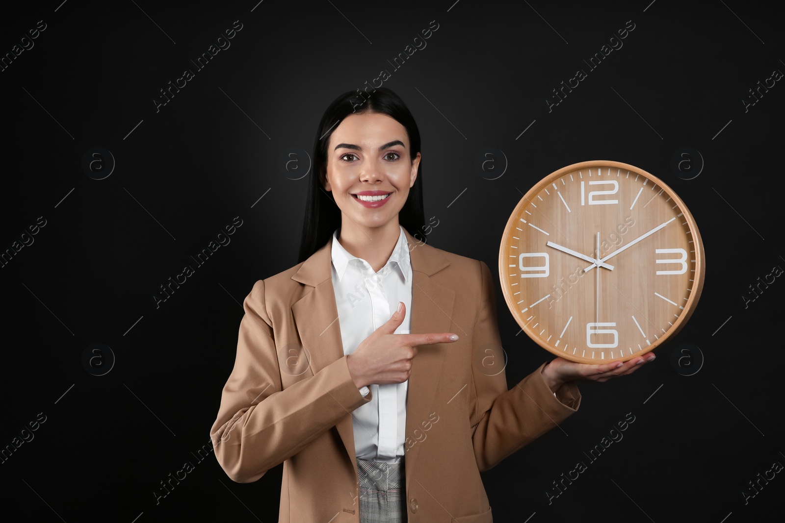 Photo of Businesswoman holding clock on black background. Time management
