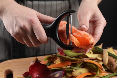 Woman peeling fresh carrot at table, closeup