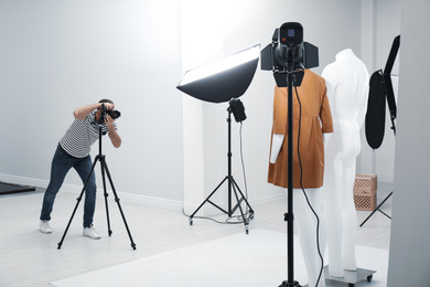 Photo of Professional photographer taking picture of ghost mannequin with stylish clothes in modern photo 
 studio