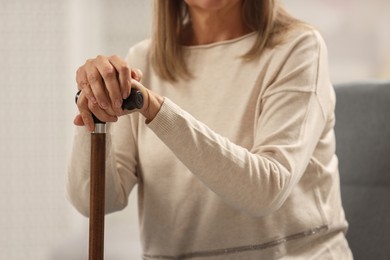 Mature woman with walking cane indoors, closeup