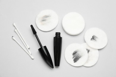 Photo of Dirty cotton pads after removing makeup, mascara and buds on light grey background, flat lay