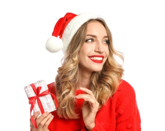 Happy young woman wearing Santa hat with Christmas gift on white background