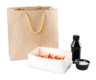 Photo of Food delivery. Box with delicious sushi rolls, paper package and soy sauce on white background