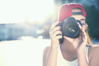 Image of Young photographer taking picture with professional camera outdoors. Space for text