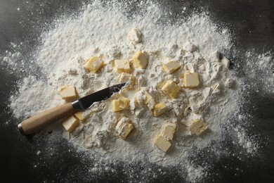 Photo of Making shortcrust pastry. Flour, butter and knife on grey table, top view