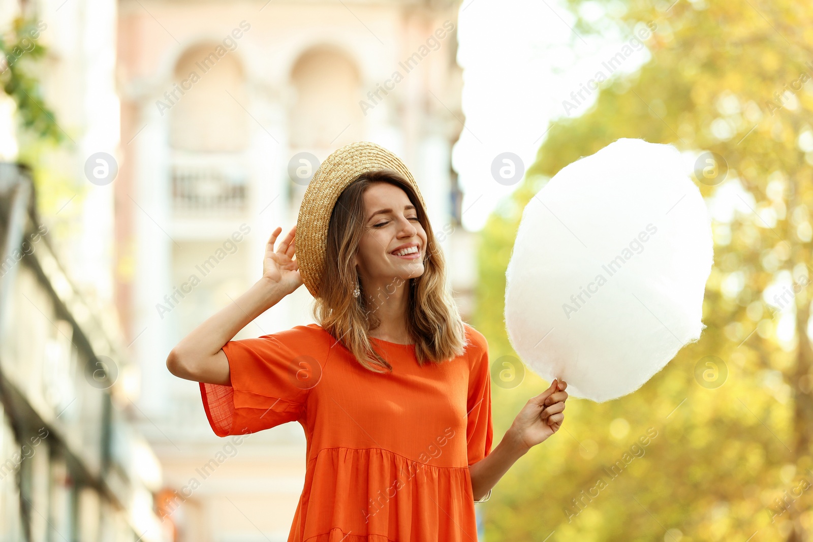 Photo of Happy young woman with cotton candy outdoors