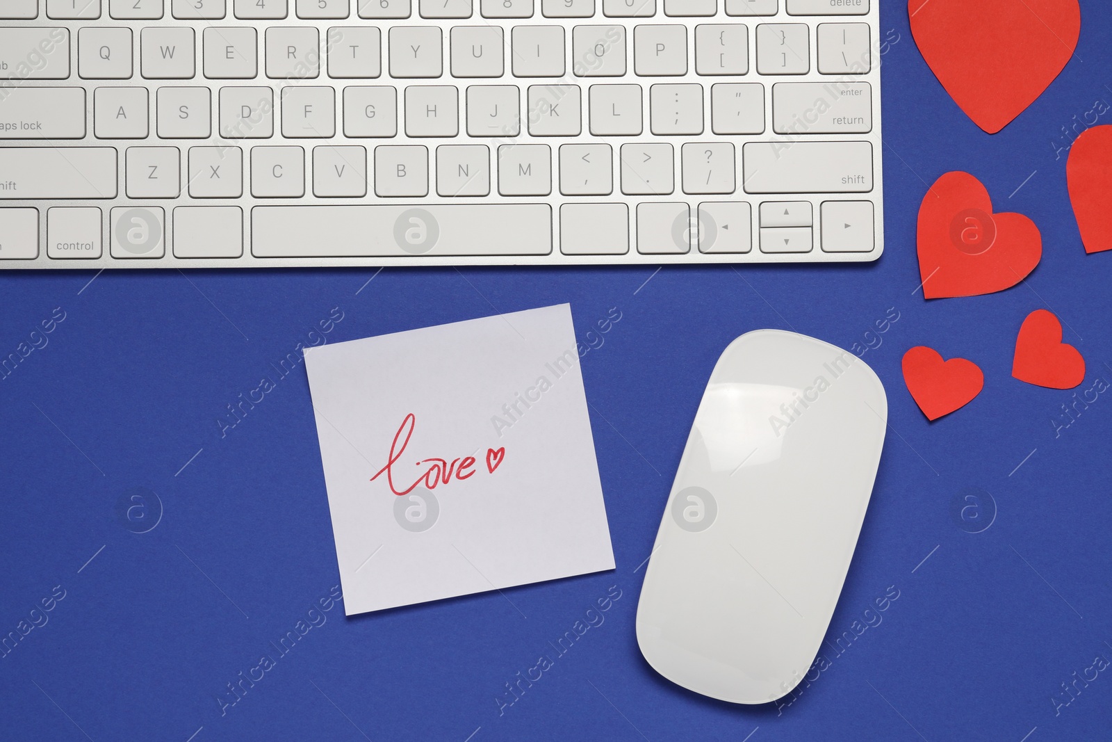 Photo of Long-distance relationship concept. Computer mouse, keyboard, love note and paper hearts on blue background, flat lay