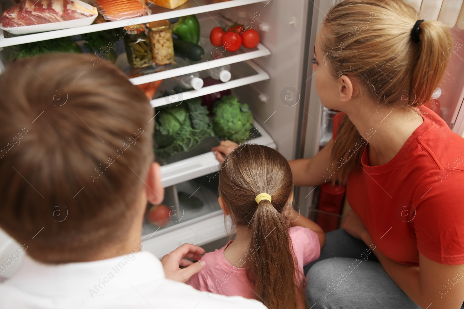 Photo of Young family choosing food in refrigerator at home
