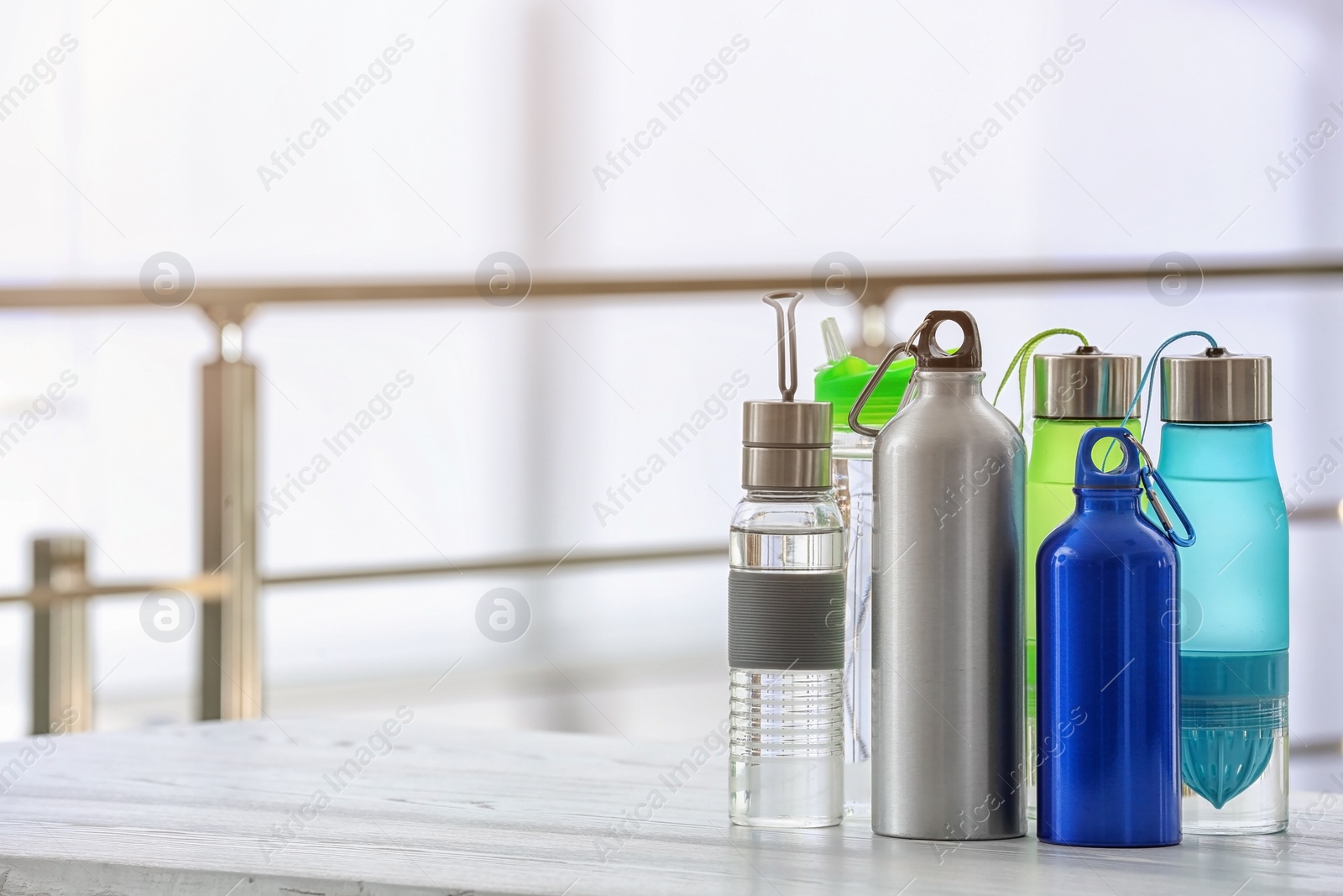 Photo of Sports water bottles on table against blurred background. Space for text