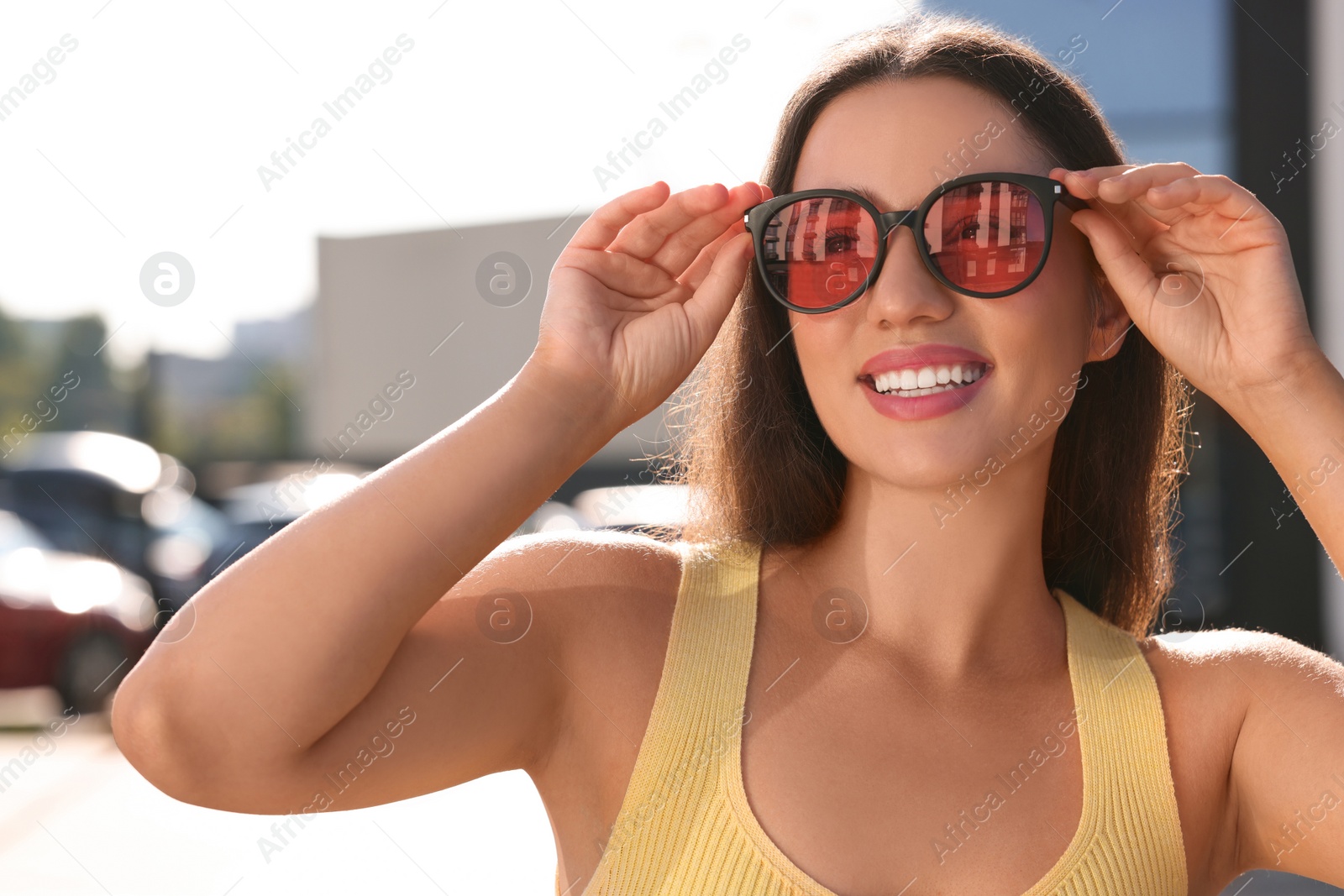 Photo of Beautiful smiling woman in sunglasses on city street, space for text