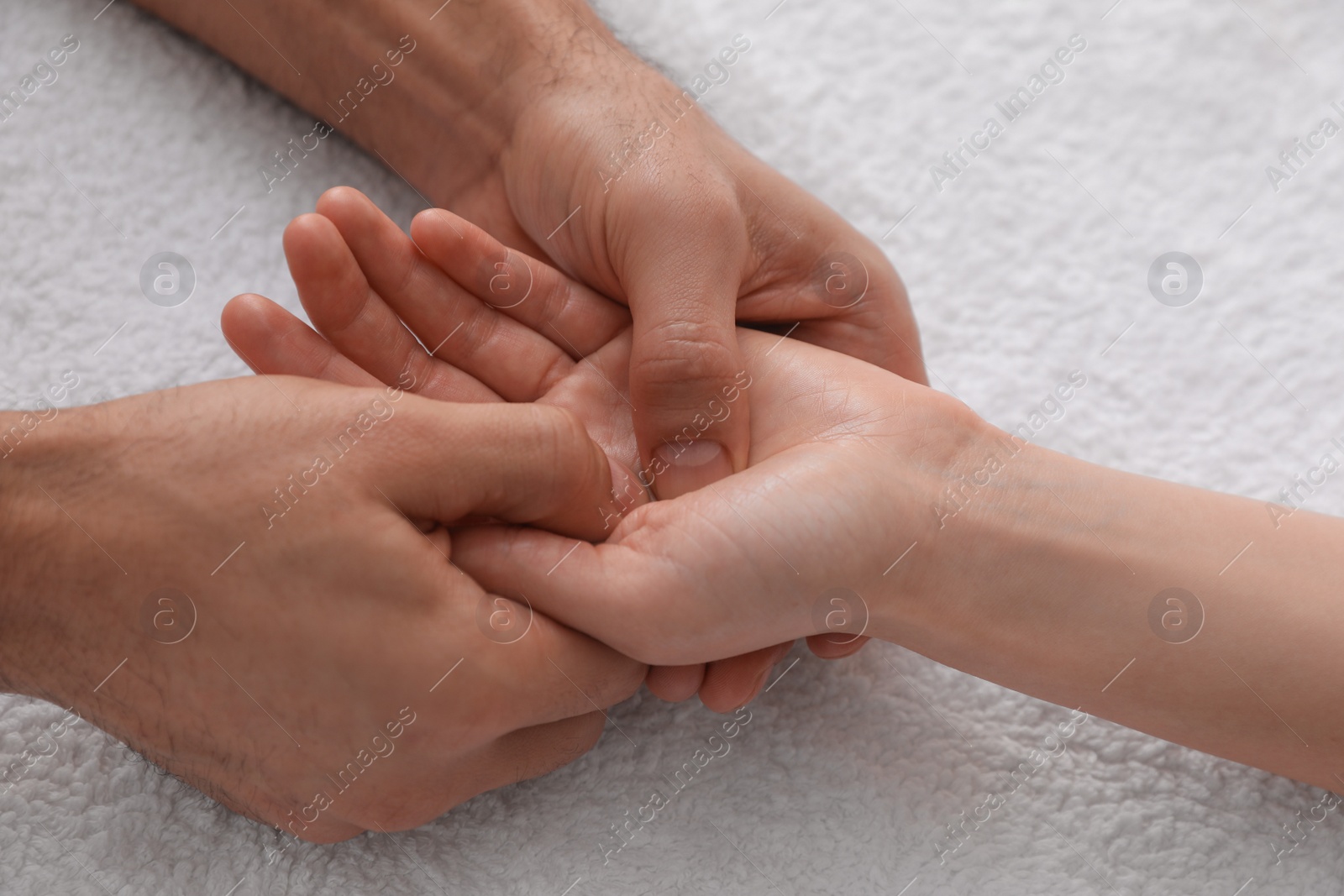 Photo of Woman receiving hand massage on soft towel, closeup