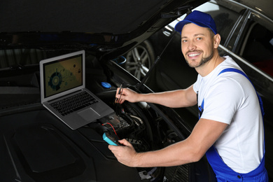 Photo of Mechanic with laptop doing car diagnostic at automobile repair shop