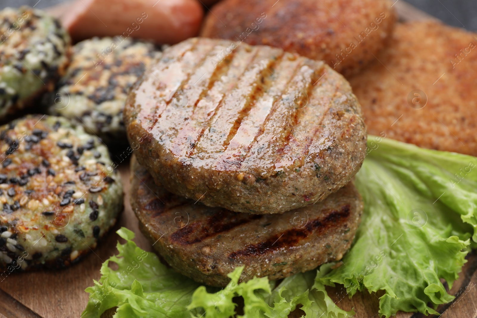 Photo of Different tasty vegan meat products on wooden board, closeup