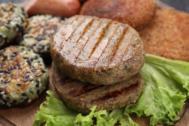 Photo of Different tasty vegan meat products on wooden board, closeup