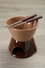 Fondue set on wooden table, closeup. Kitchen equipment