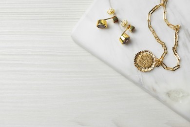 Photo of Necklace and earrings on white wooden table, top view. Space for text