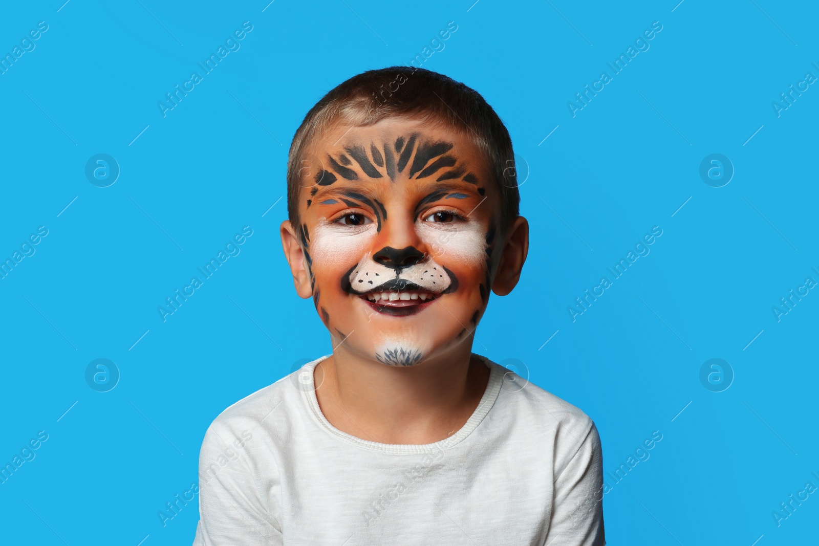 Photo of Cute little boy with face painting on blue background