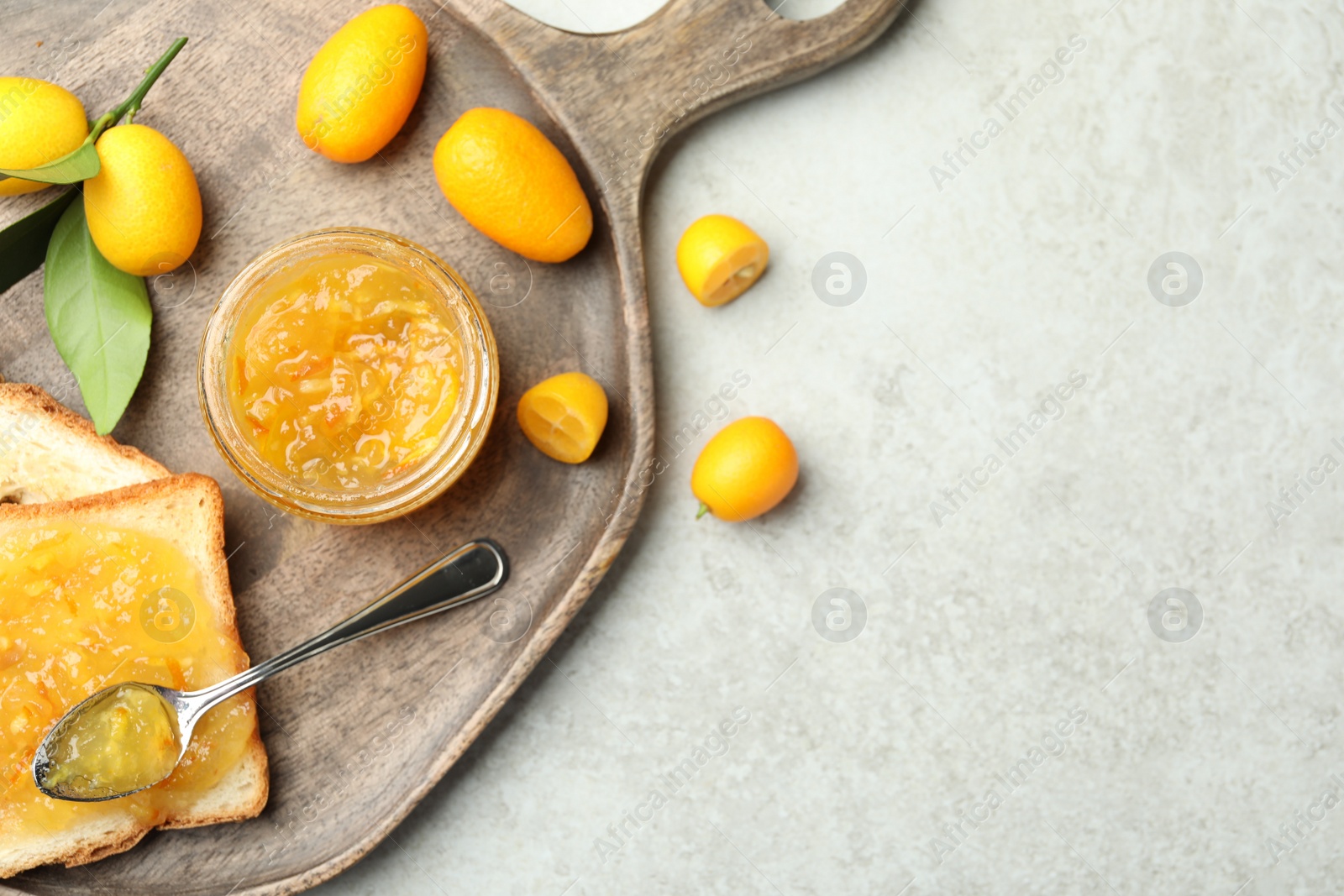 Photo of Delicious kumquat jam, tasty toasts and fresh fruits on light grey table, flat lay. Space for text
