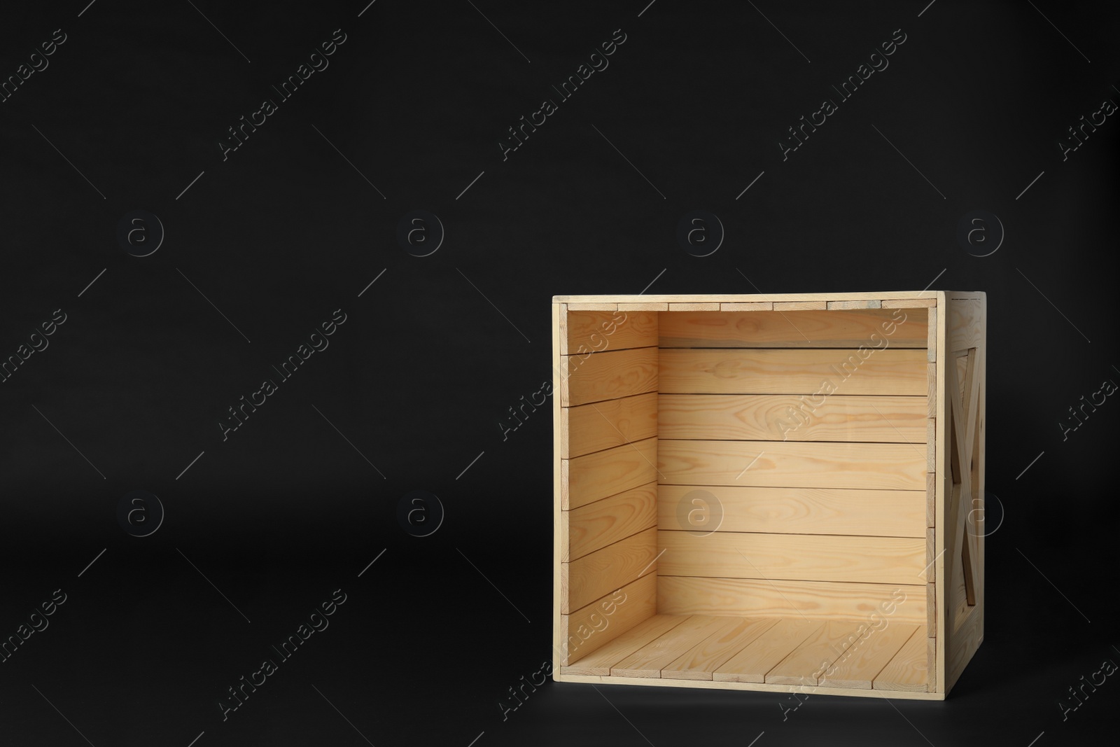 Photo of Empty wooden crate on black background, space for text. Shipping container