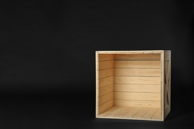 Photo of Empty wooden crate on black background, space for text. Shipping container