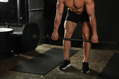 Man lifting barbell in modern gym, closeup