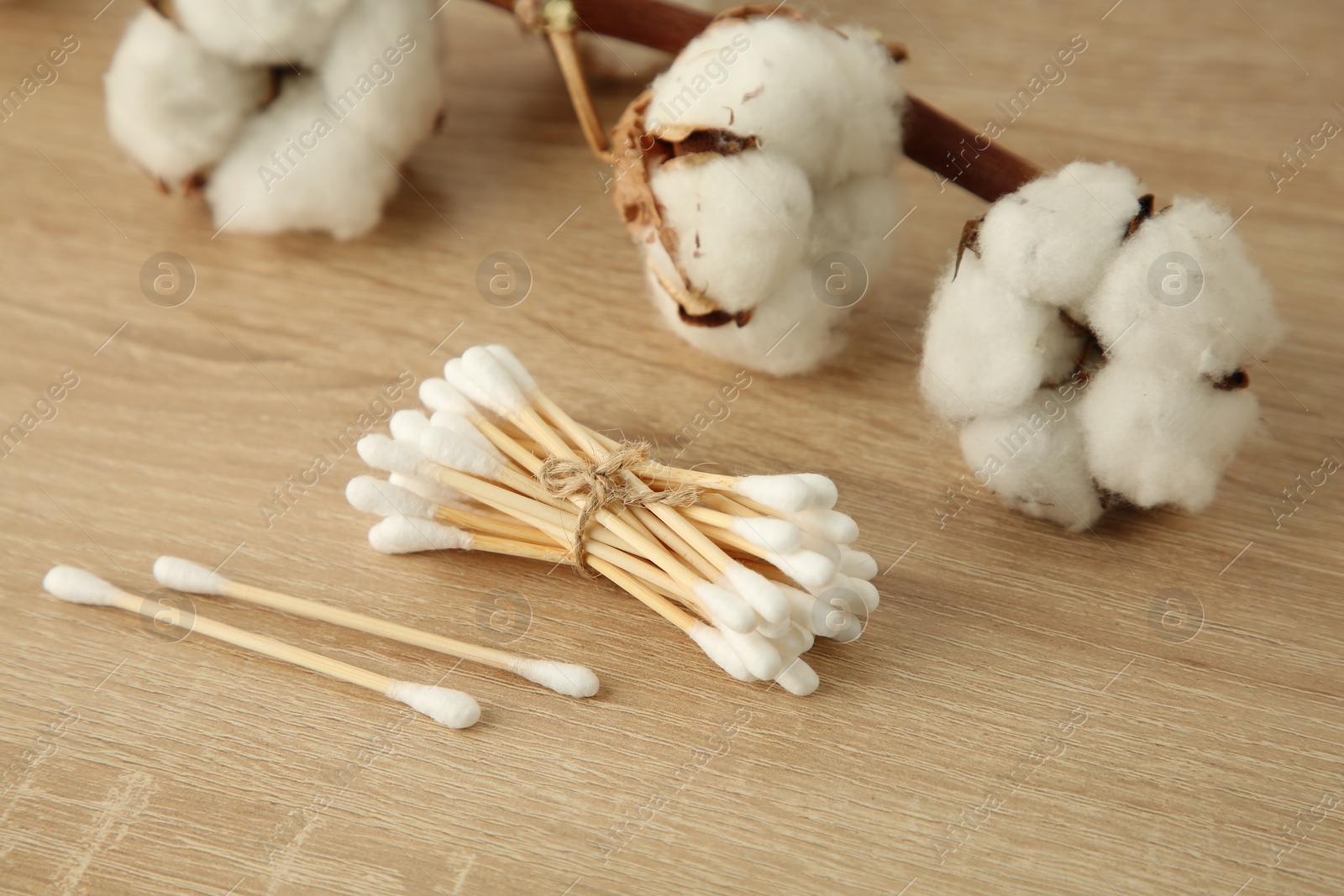 Photo of Cotton swabs and flowers on wooden table, closeup