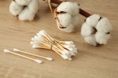 Photo of Cotton swabs and flowers on wooden table, closeup