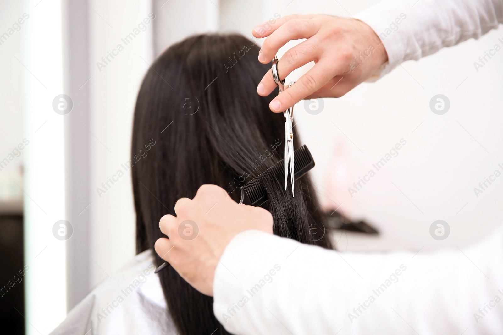 Photo of Professional male hairdresser working with client in salon