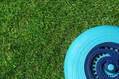 Light blue plastic frisbee disk on green grass, top view. Space for text